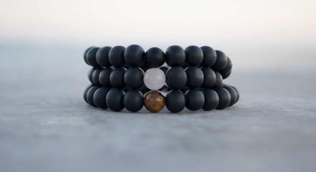 stack of athletic bracelets featuring different, natural, focal stones which are Onyx, Rose Quartz, Tiger's Eye